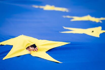 Una niña asoma la cabeza por una abertura en una bandera gigante europea, en febrero en Bucarest.