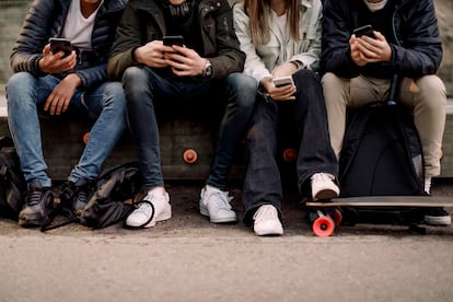 Varios jóvenes consultan sus móviles.
