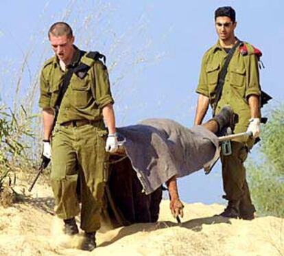 Soldados israelíes retiran el cuerpo de un palestino muerto cerca del asentamiento de Dugut, en Gaza.