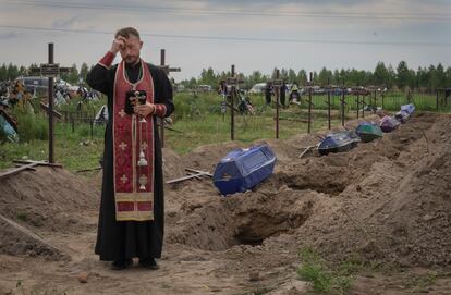 Un sacerdote reza por los civiles asesinados por las tropas rusas durante la ocupación rusa en Bucha, en las afueras de Kiev (Ucrania), este jueves. 