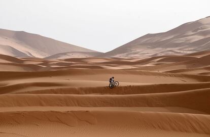 Un participante atraviesa una duna de arena con su bicicleta durante la Etapa 5 de la competición, el 3 de mayo de 2018.  