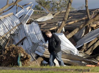Un hombre camina por delante de una de las viviendas destruidas por el tornado en Mena.
