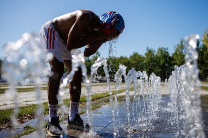 Un peatón en una fuente pública se vierte agua en Berlín.