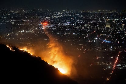 Un helicóptero de bomberos vierte agua sobre el incendio de Hollywood, la noche de este miércoles en Los Ángeles.