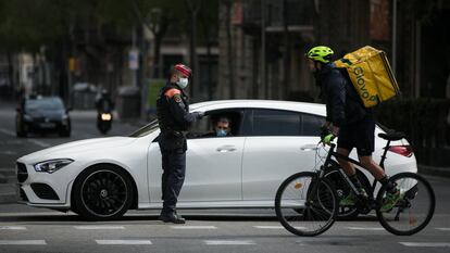 Un treballador de Glovo passa davant d'un control policial a Barcelona.