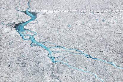 A água do degelo flui 70 quilômetros a sudeste do assentamento de Ilulissat, na Groenlândia (2014). A presença de crioconita (cinzas e fuligem), depositada na superfície da camada de gelo, aumenta a absorção de calor e acelera o processo de derretimento das geleiras.