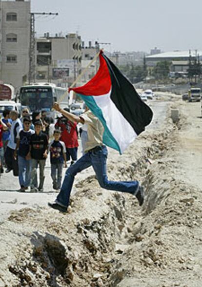 Un palestino cruza una zanja preparada para albergar el muro.