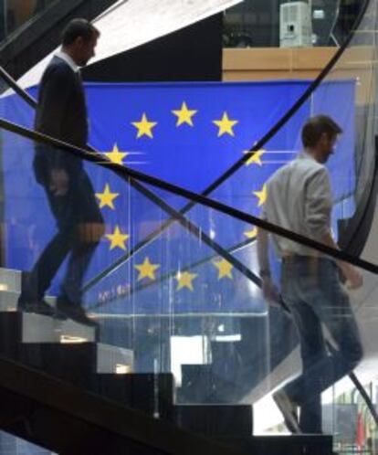 Dos hombres bajan por una escalera delante de una bandera de la Uni&oacute;n Europea, durante una sesi&oacute;n plenaria en el Parlamento en Estrasburgo.