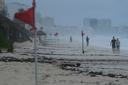 Turistas caminan junto a banderas rojas mientras el huracán Helene se acerca a la península de Yucatán, este martes en Cancún (Quintana Roo).