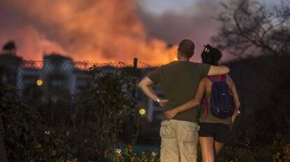 Una pareja se detiene en su paseo para ver las llamas del incendio muy cerca del hotel Aldiana.