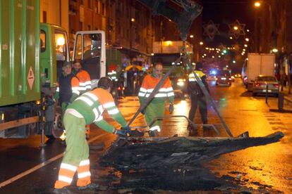 Operarios de la limpieza retiran un contenedor quemado en Bilbao.