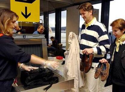 Dos pasajeros muestran sus zapatos en un control aeroportuario.