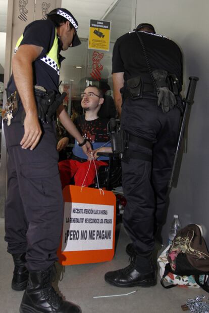 Dos policías, ayer, junto al joven que se encadenó en Alicante.