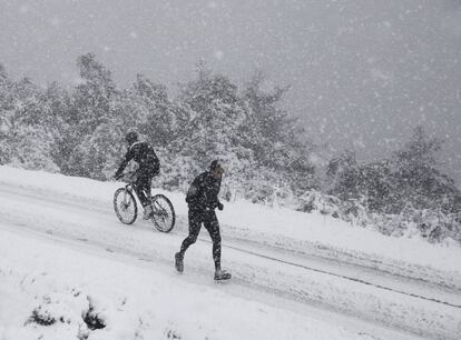 Un ciclista y un corredor practican deporte en medio de una fuerte nevada en el alto de San Cristobal en las cercanias de Pamplona.