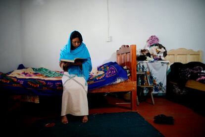 La joven Anisa lee el Corán encima de la cama de su vivienda.