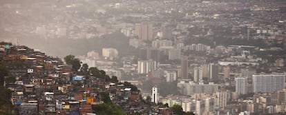 Favela em morro do Rio de Janeiro com prédios atrás.