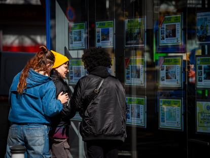 Unas jóvenes observan la oferta de pisos en alquiler de una oficina inmobiliaria de Madrid.