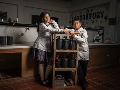 Ana Lucía Gutiérrez y Thomas Arango, estudiantes del colegio Montessori, posan junto a un generador de energía a partir de desechos de café, en Huila (Colombia), el 3 de noviembre de 2023.