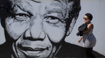 Una mujer sudafricana camina delante de un mural en recuerdo del expresidente sudafricano Nelson Mandela, en el municipio de Soweto, en las afueras de Johannesburgo. Los partidos pol&iacute;ticos sudafricanos celebrar&aacute;n m&iacute;tines de final de campa&ntilde;a este fin de semana, previos a las elecciones del pr&oacute;ximo mi&eacute;rcoles 7 de mayo de 2014, en las que es probable que el gobernante Congreso Nacional Africano vuelva al poder con una mayor&iacute;a m&aacute;s reducida debido al desontento de loas votantes por la corrupci&oacute;n en el gobierno y la desigualdad econ&oacute;mica.