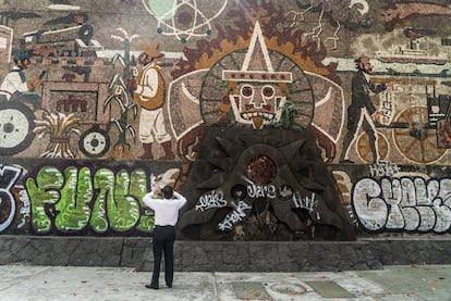 Un hombre toma una foto del mural dañado.