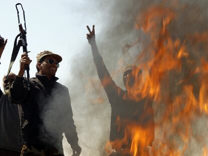 Un grupo de rebeldes junto a una hoguera en la que queman ropa de soldados de Gadafi en la carretera Bengasi-Ajdabiya.