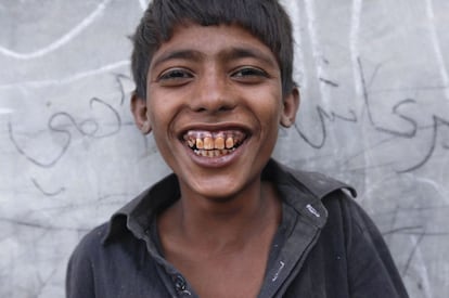 Un niño que trabaja como colector en el campo sonríe al ser fotografiado en la calle de su pueblo.