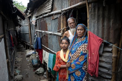 Aklima Akhtar, junto a su padre, Noor Islam, y su madre, Bilkis Begum, frente a su casa en Daca. Llegaron a la capital de Bangladés huyendo de de las crisis climática. Las inundaciones en la ciudad son menos frecuentes que en las zonas costeras.