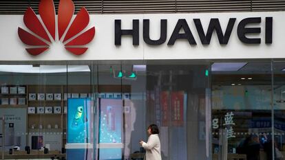 Una mujer camino frente a una tienda de Huawei en Shánghai.