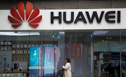 Una mujer camina frente a una tienda de Huawei en Shánghai.