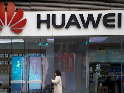 Una mujer camino frente a una tienda de Huawei en Shánghai.