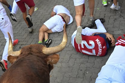 Dos mozos se protegen al paso de uno de los toros de la ganadería Jandilla.
