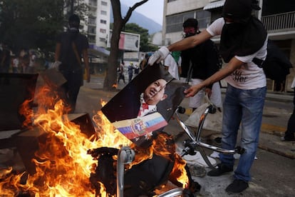 Un manifestante antigubernamental quema un cartel del fallecido presidente de Venezuela, Hugo Chávez, después de saquear un edificio público en Caracas.