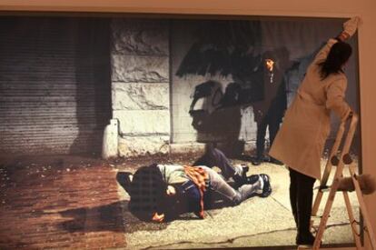 Una operaria limpia la obra <i>Una pelea en la acera</i>, de Jeff Wall, que se expone en el IVAM.