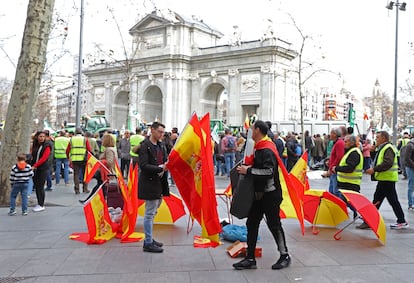 Un vendedor ambulante vende paraguas y banderas de España durante la manifestación de agricultores, este miércoles en Madrid. 