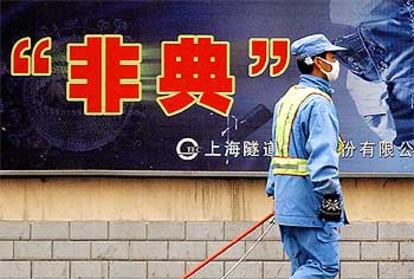 Un barrendero pasa ante un cartel de la campaña contra la propagación de la epidemia en Shanghai.