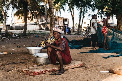 La madre de Kessah espera en la orilla de Maranatha Beach a que su hijo llegue de la jornada de trabajo nocturna. Junto a ella, la cesta de metal para almacenar la mercancía.