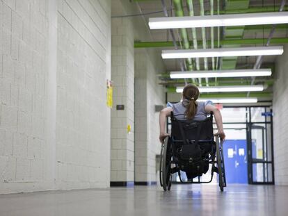 Una mujer en silla de ruedas en el pasillo de una institución educativa