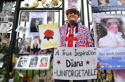 Un seguidor de Lady Di posa junto a los recuerdos de Diana de Gales, colocados a las puertas del Palacio de Kensington en Londres.