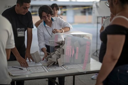 Una funcionaria electoral vacía una urna para contar los votos, en el municipio mexiquense de Ecatpec