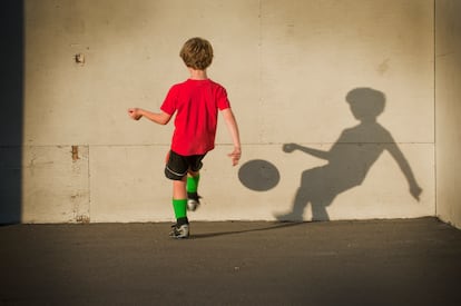 Un niño juega al fútbol solo.