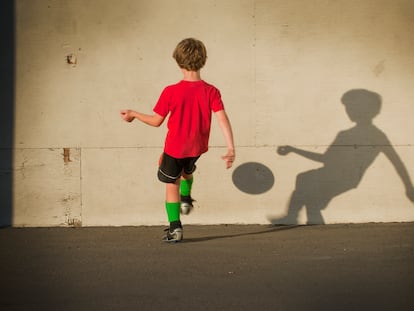 Un niño juega al fútbol solo.