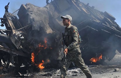 Combatientes talibanes incendian vehículos militares de la OTAN a las afueras de Jalalabad, Afganistán. En la imagen, un militar afgano camina junto a uno de los vehículos incendiados.