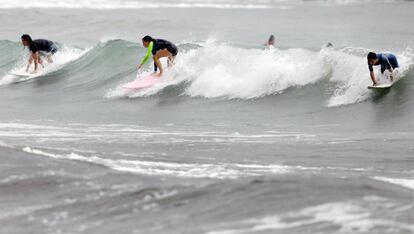 Varios jóvenes practican surf, este lunes, en la playa de la Malvarrosa de Valencia.