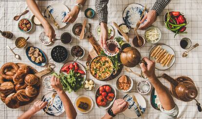 Flat-lay family having traditional Turkish breakfast over chekered tablecloth