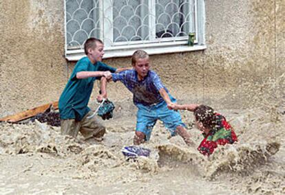 Dos niños ayudan a otro, atrapado por una riada, en la ciudad rusa de Novorossiisk.