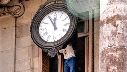 Un operari canvia l'hora del rellotge de l'Ajuntament de Barcelona.