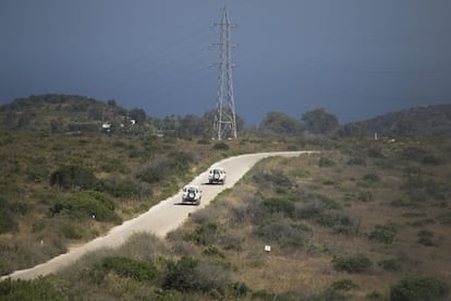 Dos coches de la Brigada de Investigación de Incendios Forestales (BIIF), pasan junto a una línea electrica. Una de las causas más comunes de incendio forestal son el mal estado de las líneas de baja tensión.