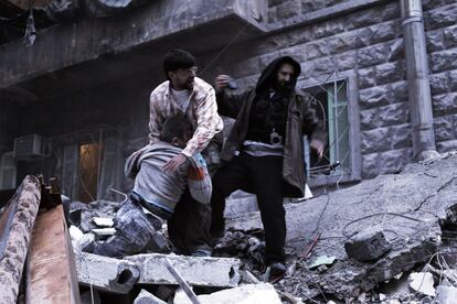 Dos hombres rescatan el cuerpo de un herido de los escombros del edificio derrumbado por un misil en el barrio de Al Mashad en Alepo