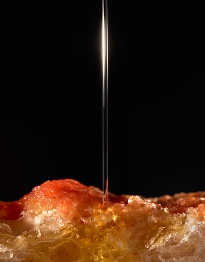 Un hermoso chorro de aceite de oliva virgen extra cae sobre una torrada de pan con tomate.