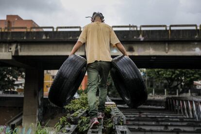 Un simpatizante de la oposición carga llantas para construir una barricada, en una protesta en contra de el gobierno de Nicolás Maduro, en Caracas, Venezuela.